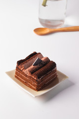 The chocolate cake is layered in a plate on a white background.