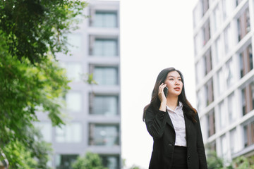 Fototapeta premium Beautiful asian business woman talking on cellphone while walking outdoor