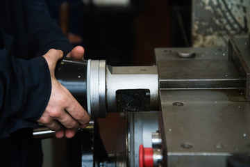 Heavy industrial worker performs a mechanical operation on a machine for the production of steel structures