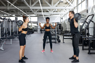 professional sportsman teach girls to pump muscles with the use of weights, gives instructions on how to perform the exercises correctly