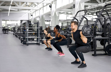 caucasian trainer is teaching exercises with weights to diverse attractive women, dumbbell, barbell lifting course to increase body muscles to be strong