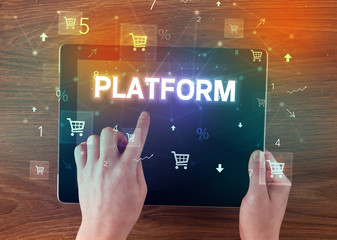 Close-up of a hand holding tablet with PLATFORM inscription, online shopping concept