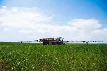 Tractor spraying wheat field with sprayer