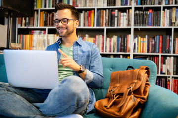 Smiling male student working and studying in a library