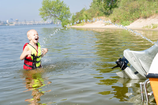 The child plays, catches water splashes from the pump. Boating on the lake.