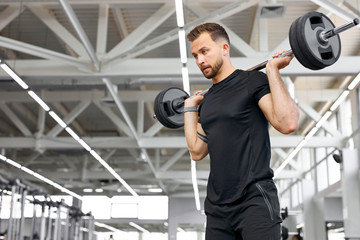 caucasian athletic man pumping up muscles with barbells, strong man under physical exertion pumping up bicep muscle with heavy weight in gym