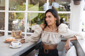 Sensual confident woman in stylish clothes enjoying coffee coffeeshop. Attractive female model sitting cafe, having lunch with admirer, smiling look away pleased, breakfast at outdoor restaurant