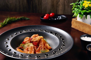 Shrimp salad with vegetables. In a black dish. Beautiful presentation of dishes for a restaurant.