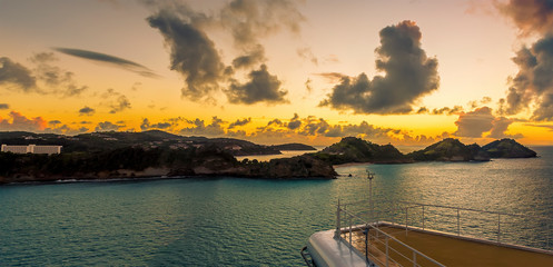A cruise ship sails down the coast of Antigua at sunset