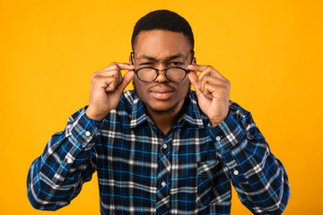 Man In Eyeglasses Looking At Camera Squinting Eyes, Yellow Background