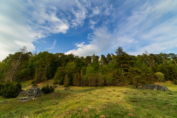 Fototapeta na wymiar Germany, Wide angle view with smooth moving clouds above rock formations in wental valley in swabian alb landscape at the edge of the forest