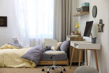 Stylish teenager's room interior with comfortable bed and workplace