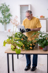 Fototapeta na wymiar Old male gardener with plants indoors