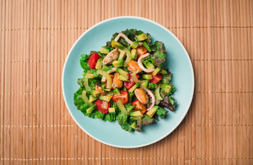 Flat lay - Asian Salad with seafood with avocado, tomatoes, octopus and mussels in blue plate on wooden table. Concept of healthy diet food.