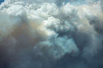 Blue and white sky puffy cumulonimbus clouds and smoke from a large wildfire