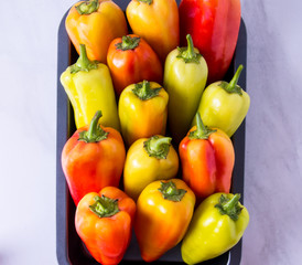 Red yellow and green pepper on a tray, top view
