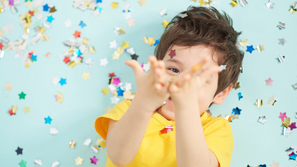 happy birthday child. Photo of charming cute fascinating nice little boy blowing confetti at you to show her festive mood with emotional face expression.