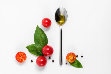 Creative mockup with tomato slices, basil leaves and a spoonful of olive oil. Flat lay, top view. Food concept. Vegetables isolated on a white background.