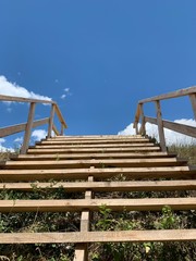 Wooden staircase to the sky. Wooden steps and railings against the blue sky. Design for walking uphill.