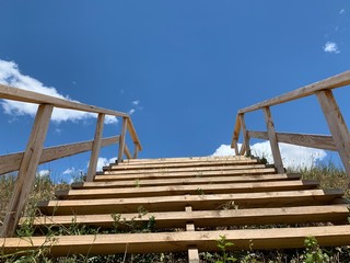 Wooden staircase to the sky. Wooden steps and railings against the blue sky. Design for walking uphill.