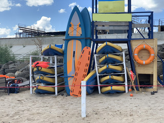 Surfboards are stacked on the shore. Beach equipment near the rescue station. Rubber boats and...