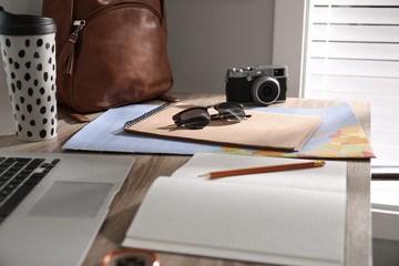 Notebook and travel accessories on wooden table. Planning summer vacation trip