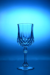 Wineglass on the light background. Fine cristal glassware concept. Vertical, toned in blue