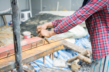 The hands of the builder are bending the iron at site construction