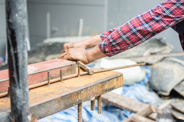 The hands of the builder are bending the iron at site construction