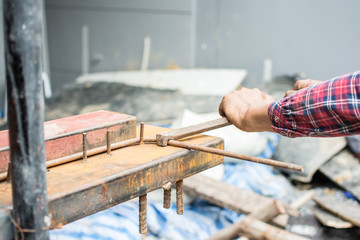 The hands of the builder are bending the iron at site construction
