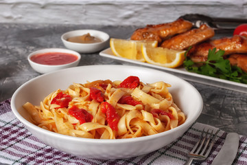 Pasta with tomatoes and grilled wings. Italian food. Italian Cuisine. The concept of tasty and healthy food.