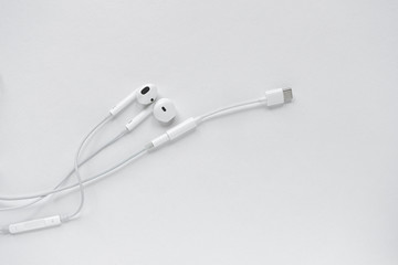 USB to 3.5mm type c headphone cable adapter on smartphone next to headphones with headphone cable. White headphones lying on a white background. Contemporary music concept. Audio technology.