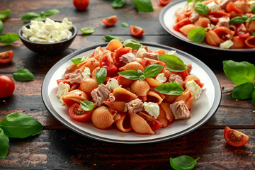 Conchiglie Tuna pasta with tomato sauce, feta cheese and basil on wooden table. healthy food
