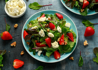 Goats cheese and strawberry summer salad served with nigella and sesame seeds drizzled with runny honey