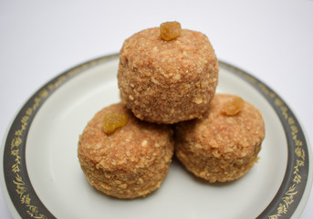 Closeup of popular Indian sweet balls Laddu or ladoo made from chapati roti powdered mashed and made in to big ball. Decorated with raisin kismis served in plate. Prashad for festivals
