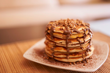 Delicious plate of pancakes with peanut syrup, cocoa and toppings