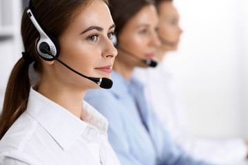 Call center. Group of operators at work. Focus on beautiful business woman in headset