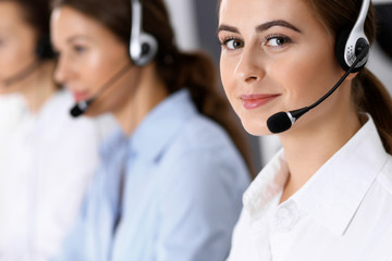 Call center. Group of operators at work. Focus on beautiful business woman in headset
