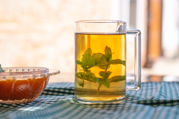 Flavored green tea with mint in a transparent mug. Open-air morning tea