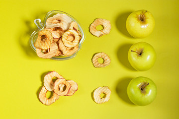 Natural apple chips in a glass bowl on a green background. Healthy vegan vegetarian fruit snacks. Organic food for weight loss