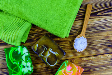 Pieces of the handmade soap, towel and spoon with sea salt on wooden background. Top view