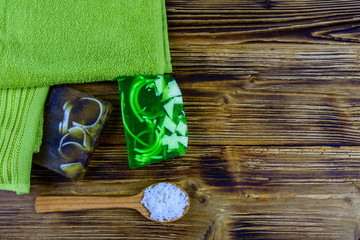 Pieces of the handmade soap, towel and spoon with sea salt on wooden background. Top view