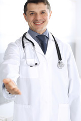 Fototapeta premium Doctor man cheerful smiling at camera, helping hand. Perfect medical service in clinic. Happy future in medicine and healthcare