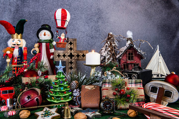 still life of vintage Christmas presents and decorations including stereoscope and old camera with snow man and wooden cross with balloon flying Santa