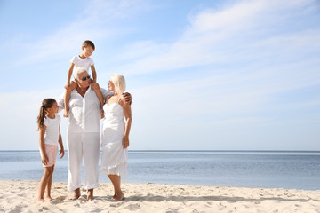 Fototapeta na wymiar Cute little children with grandparents spending time together on sea beach