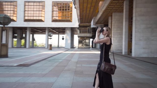 Woman takes photos with camera of architecture of modern buildings. Action. Woman with professional camera takes pictures of buildings of modern architecture