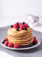 Homemade pancakes with raspberries and blueberries on grey napkin.
