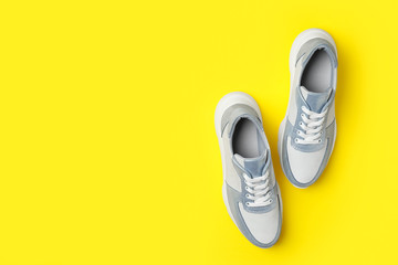 Stylish sneakers on yellow background, flat lay. Space for text