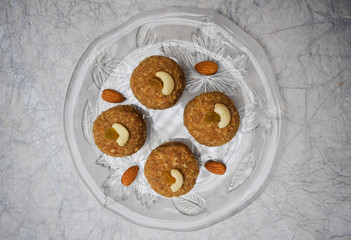 Top view of Laddu, ladoos Indian sweet balls on transparent crockery plate decorated with almonds and cashewnuts. For festivals like Ganesh chaturthi