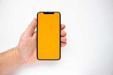 A person holding an Smart Phone with a orange screen on a white background.